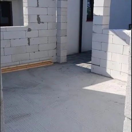 Casă la roșu văzută dinspre curtea betonată