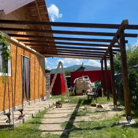 Pergolă din lemn de-a lungul casei